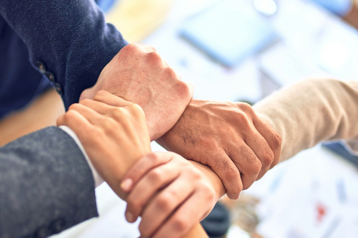 Team members joining hands over a worktable